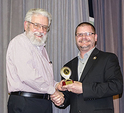 2025 NWOSU Homecoming Parade Marshal, Dr. Ken Brown (left), receives the 2017 Alva Chamber of Commerce Volunteer of the Year Award from Alva mayor Kelly Parker (right).