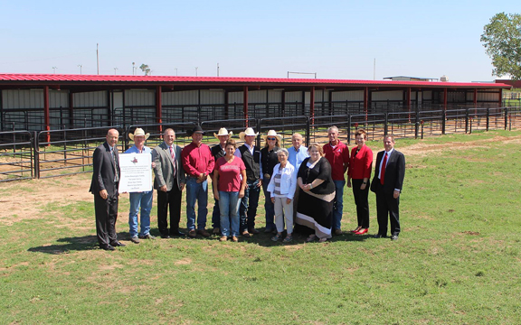 Rodeo project donors and members of the Northwestern Oklahoma State University administration stand in front of new pens constructed at the Campbell Rodeo Complex.