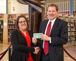 Dr. David Pecha (right) presents $25 of Alva Chamber of Commerce “Chamber Bucks” to homecoming theme contest winner Shawna Gilbert (left), assistant professor of library science and access services librarian of J.W. Martin Library.