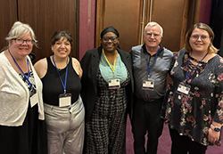 Five Northwestern Oklahoma State University faculty members standing together in a hallway, wearing conference lanyards, at the 2026 AI Symposium for Oklahoma Educators. From left: Dr. Shannon Leaper, Dr. Christina Xan, Dr. Roxie James, Dr. Barry Evans and Sarah Martin.
