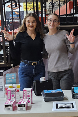 Jenna Maier (left), a senior social work major from Alva, and Hadley Bohlen (right), a Northwestern senior accounting major from Ringwood, pose for a photo at a Higher Education Prevention Services booth at a Northwestern Athletics event in Percefull Fieldhouse.