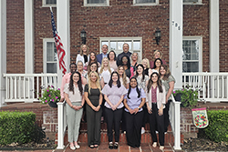 Students, faculty, and benefactors of Northwestern Oklahoma State University's Wisdom Family Foundation Doctoral Program for Rural Nursing Practice gather for a group photo at the President's House during the 2025 summer residency week. The group includes 14 DNP students, nursing faculty members, program benefactors including Dr. Peggy Wisdom, Todd Holder and Northwestern President Dr. Bo Hannaford.