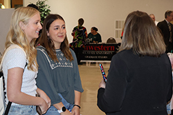 Two Northwestern students discuss employment opportunities with representatives from local education institutions at a previous career fair event, demonstrating the networking opportunities available at Northwestern's Education Career Fair.