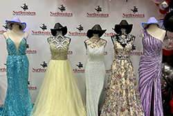 A group of mannequins in front of a Northwestern backdrop, showcasing donated prom dresses and accessories.