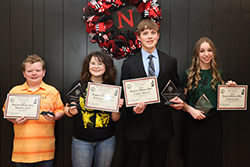 Four students stand in a row holding 2026 Northwest Oklahoma Regional Science Fair certificates and trophy awards in front of a black wall decorated with a red and black Northwestern Rangers wreath. 