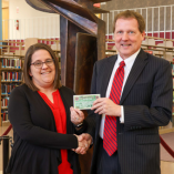 Dr. David Pecha (right) presents $25 of Alva Chamber of Commerce “Chamber Bucks” to homecoming theme contest winner Shawna Gilbert (left), assistant professor of library science and access services librarian of J.W. Martin Library.