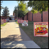 A campus sidewalk lined with hand-painted spirit boards created by Northwestern Oklahoma State University clubs and organizations. The closest board reads 