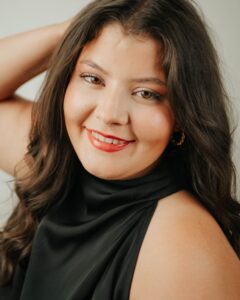 Christina Salinas, Miss Northwestern’s Teen contestant, in a black sleeveless top with one hand in her hair, against a gray background.
