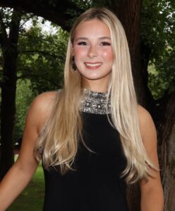 Trinity Tuell, Miss Northwestern contestant, in a black sleeveless top with a jeweled neckline, standing under a tree.