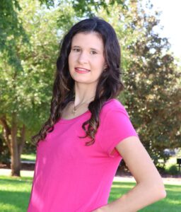 Lillian Kalblinger, Miss Northwestern contestant, in a pink top, standing on a lawn in front of trees.