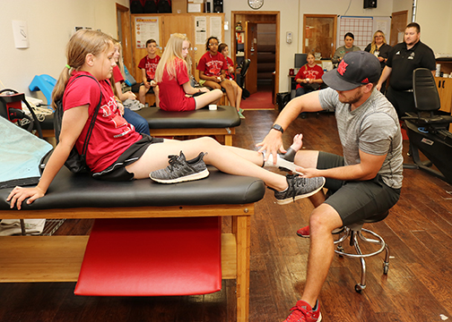MASH Camper Tiffany Stevens volunteered to have her ankle taped by Garrett Thompson while Keith Wear talks about the job of an athletic trainer.