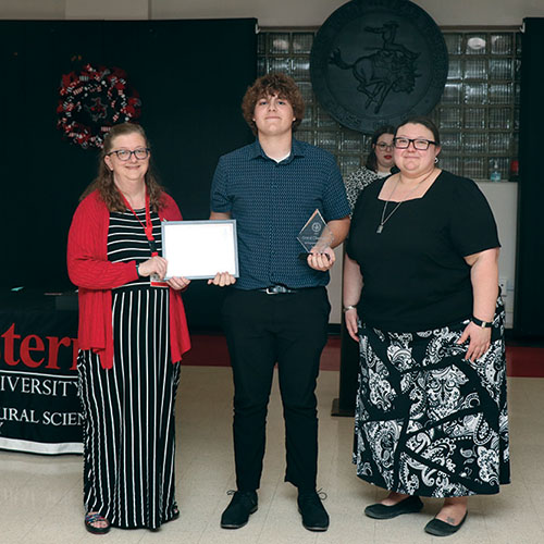 Dr. Jennifer Sattler, Northwestern department of natural science chair and associate professor of physics (left) and Dr. Mary Riegel, Northwestern professor of mathematics (right) present the Division I Grand Champion award to Ethan Todd from Northwest Technology Center (Fairview).