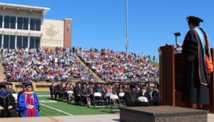 Croud on bleachers while student gives speech on podiu,m