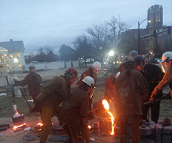 Northwestern students assist pouring molten iron into an iron mold.