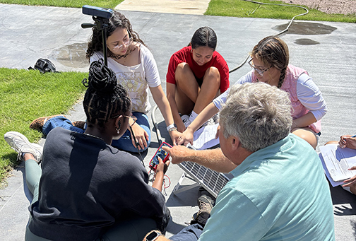 Terry Benton with NextEra Energy helps students at the recent STEM Camp at Northwestern measure the amount of power generated by the solar panel. The students adjusted the panel to face direct sunlight, then used a multimeter to measure the voltage.