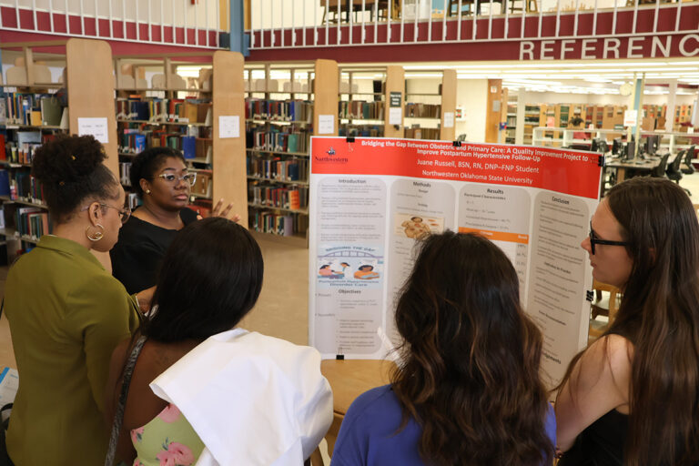 Northwestern Oklahoma State University DNP graduate Juane Russell presents a research poster titled “Bridging the Gap Between Obstetric and Primary Care” to a group of attendees in J.W. Martin Library.
