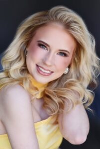 Olivia Church, Miss Northwestern’s Teen contestant, in a yellow top with one hand in her hair, in a studio portrait.