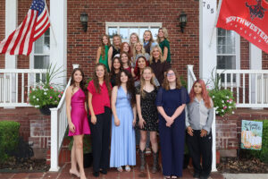 Seventeen high school seniors competing in Northwestern Oklahoma State University's 74th Miss Cinderella Pageant stand on the steps of a brick house in Alva, Oklahoma, each raising the Northwestern “Ride Rangers Ride” hand sign, with a red Northwestern Rangers flag and an American flag beside them. Names in rows: (back row, left to right) Ava Schultz, Miss Kremlin-Hillsdale; Khloe Cummings, Miss Mooreland; Mary Katherine Teal, Miss Laverne; Kaitlyn Culp, Miss Woodward; and Embrie Crawford, Miss Ringwood; (second row, left to right) Danica Gleason, Miss Medicine Lodge (Kansas); Kinsley Acre, Miss Taloga; and Kassie Irwin, Miss Aline-Cleo; (third row, left to right) Kaycie Shelton, Miss Cherokee; Amelie Burgtorf, Miss Shattuck; and Pricilla Parada, Miss Sharon-Mutual; (front row, left to right) Avyn Harland, Miss Buffalo; Kylee Logsdon, Miss Alva; Rebecka Carlson, Miss Burlington; Malinda Sanpaka, Miss South Barber (Kansas); Bristen Robertson, Miss Arnett; and Shai-Ann Nichole Chavez, Miss Timberlake.