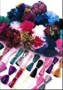 A pile of paper pomps in many colors alongside rolled bundles of fringe.
